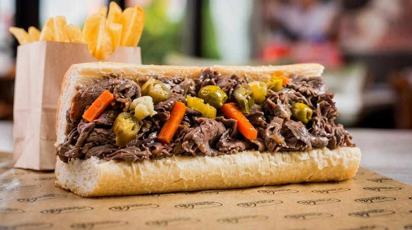 A large Italian beef sandwich with giardiniera and a side of crinkle-cut fries.